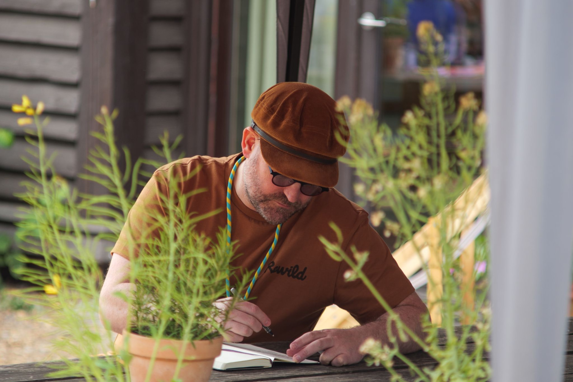 A participant writing in a notebook outdoors, surrounded by plants